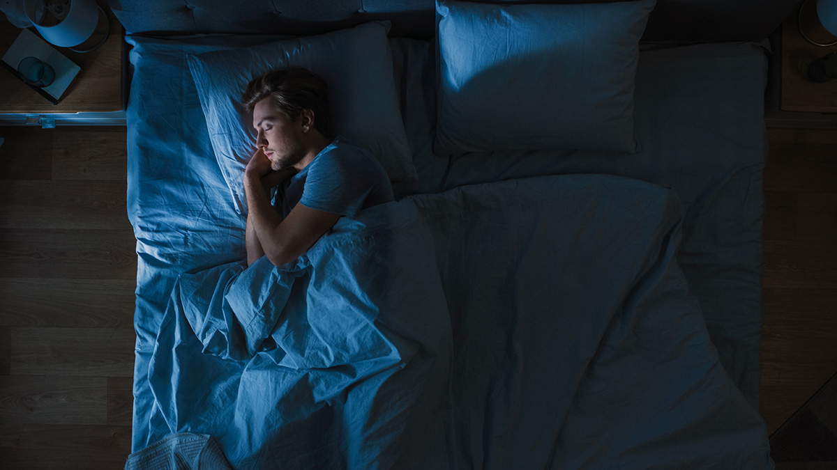 Young Man Sleeping Cozily on a Bed in His Bedroom at Night.